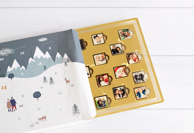 Calendrier de l'Avent chocolat personnalisé avec un design de montagne enneigée sur la couverture, révélant des chocolats avec des dessus photo personnalisés à l'intérieur.