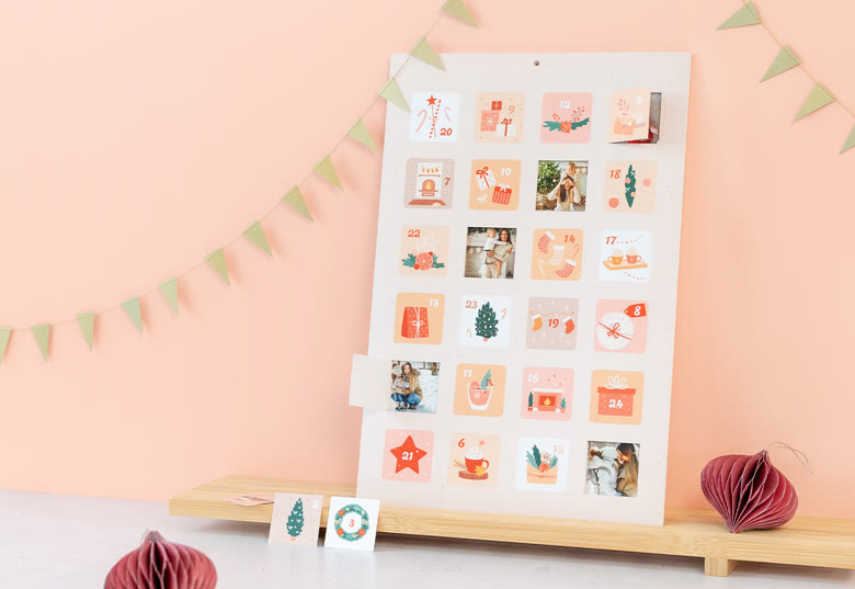 Calendrier de l'Avent photos personnalisé avec des illustrations festives et des images personnalisées, affiché sur un fond pêche avec des fanions verts.