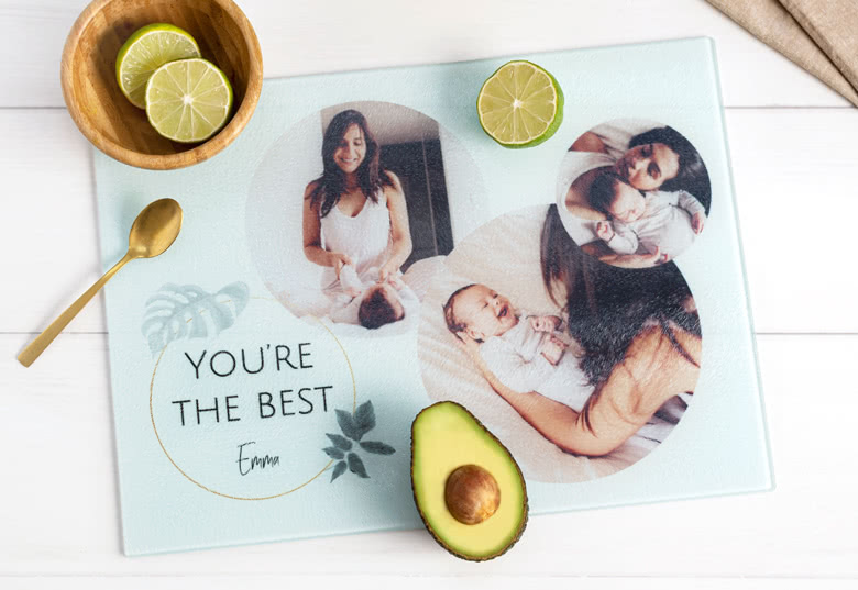 Personalised cutting board with three photos of a woman and baby, text "You’re the best Emma", and leaf illustrations on a light background.