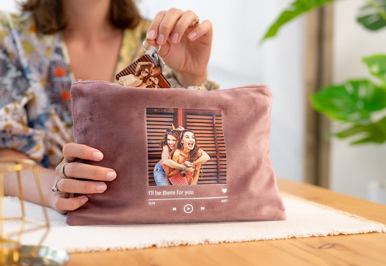 Trousse de toilette en velours rose avec photo et texte personnalisés, exposée sur une table en bois.