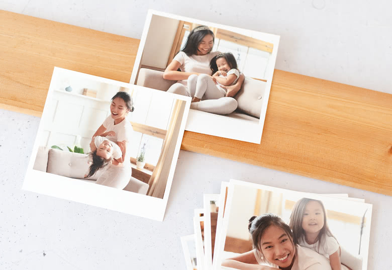 Cartes de recharge photo personnalisées affichant des moments en famille, featuring a woman and child, avec des bordures blanches sur une surface en bois clair.