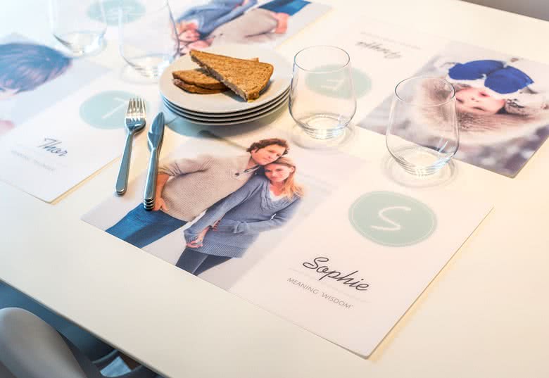 Gepersonaliseerde plastic placemat met persoonlijke foto's en namen in zachte tinten.