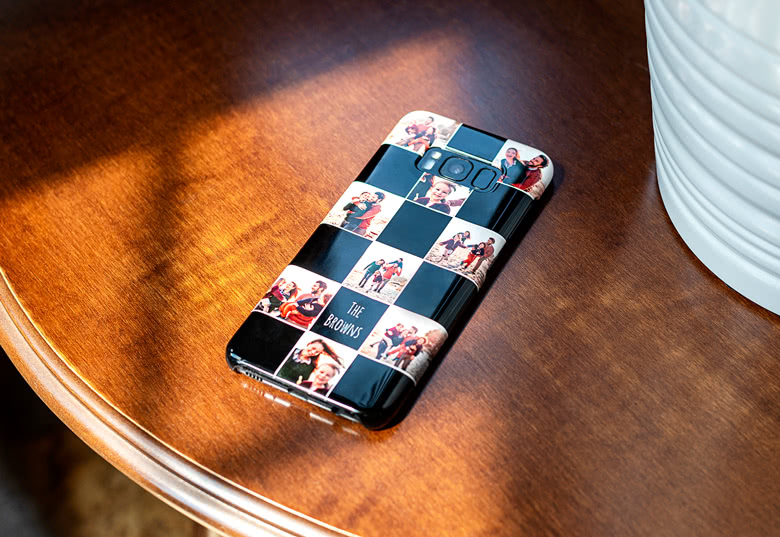 Customised black Samsung phone case with a photo collage and text "THE BROWNS" on a wooden surface.