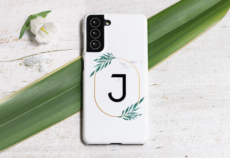 Coque Samsung blanche personnalisée avec un monogramme 'J' dans un cercle doré, entouré de feuillage vert.