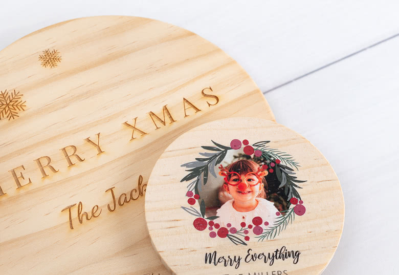 Gepersonaliseerde houten deksels voor geurkaarsen met feestelijke ontwerpen. Een deksel heeft een foto en een krans, de andere zegt "Merry Xmas", gegraveerd op het houten deksel.