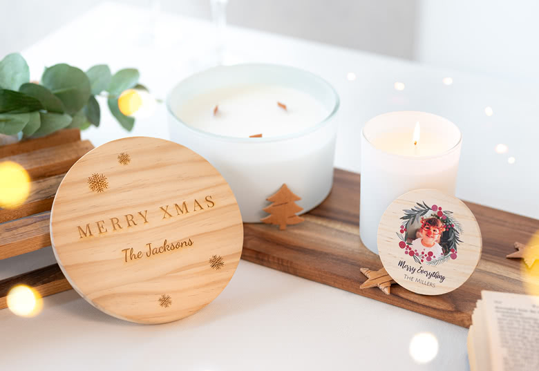 Two personalised scented candles; one with a wooden lid engraved "Merry Xmas The Jacksons" and the other featuring a festive photo.