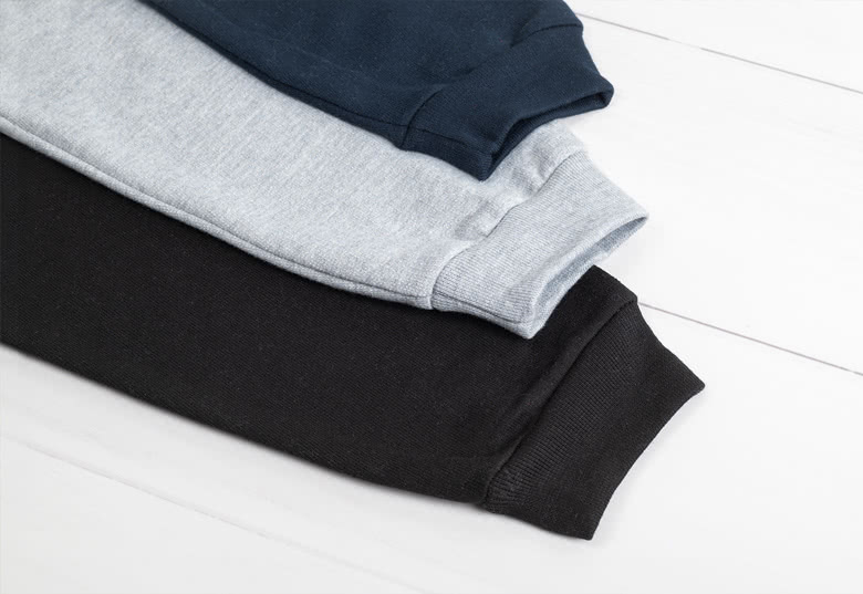 Stapel gepersonaliseerde kindersweaters in marineblauw, grijs, en zwart.