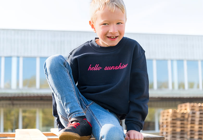 Child in a black sweatshirt with "hello sunshine" in pink script.