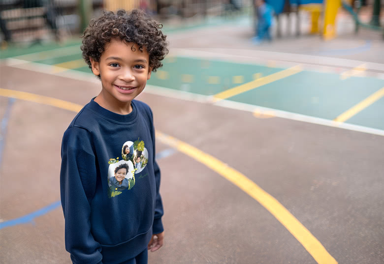 Kind in een marineblauwe sweater met gepersonaliseerd fotodesign aan de voorkant.