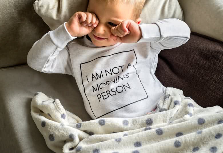Child in a white personalised sweatshirt with "I AM NOT A MORNING PERSON" text.