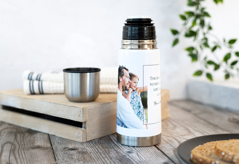 Personalised thermos flask with a custom photo and text, featuring a silver base, black lid, and a white body displaying the image and message.